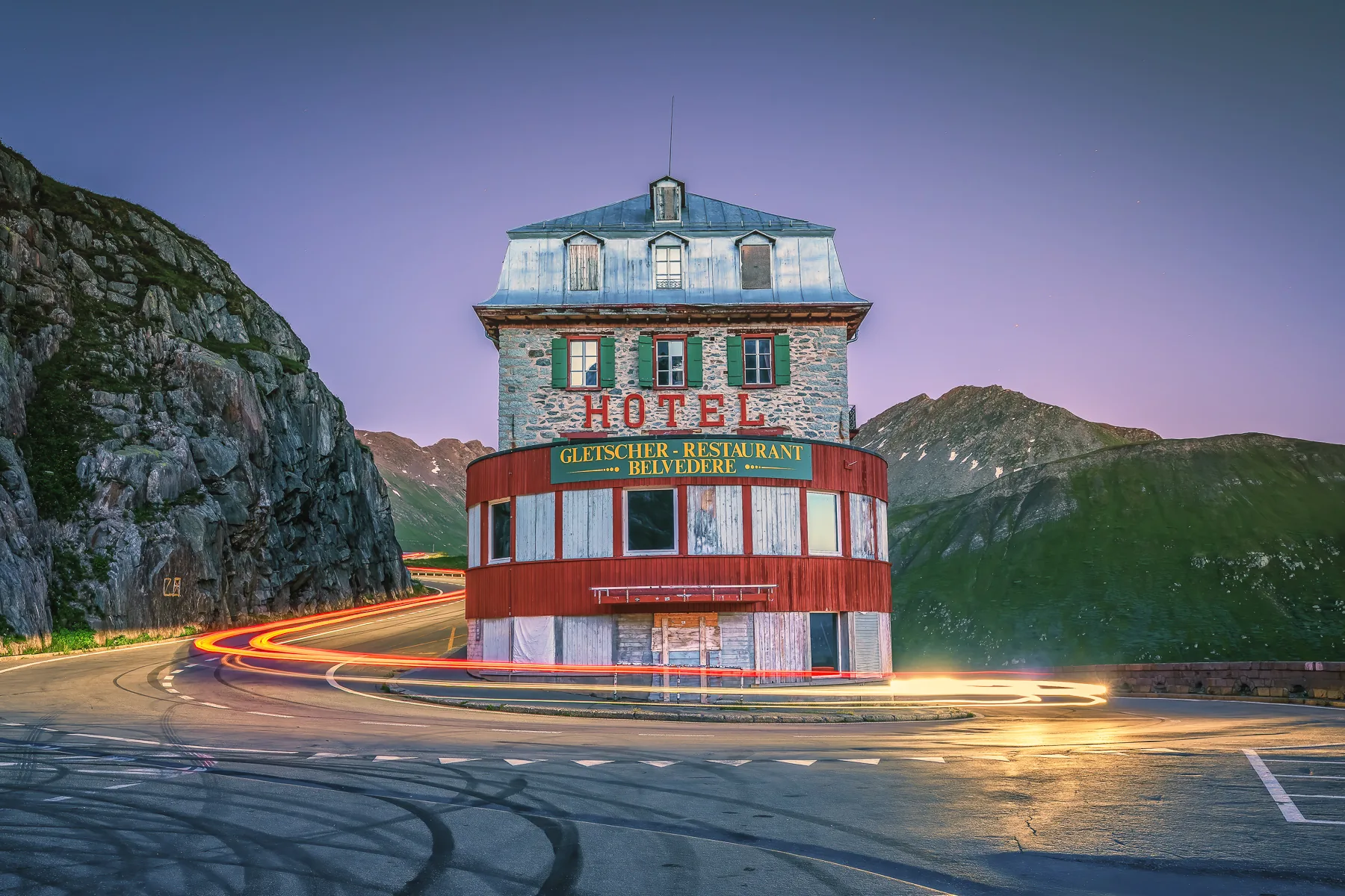 Verlassenes Hotel Belvedere am Furkapass mit Lichtspuren von Autos bei Abenddämmerung, Schweizer Alpen Uri