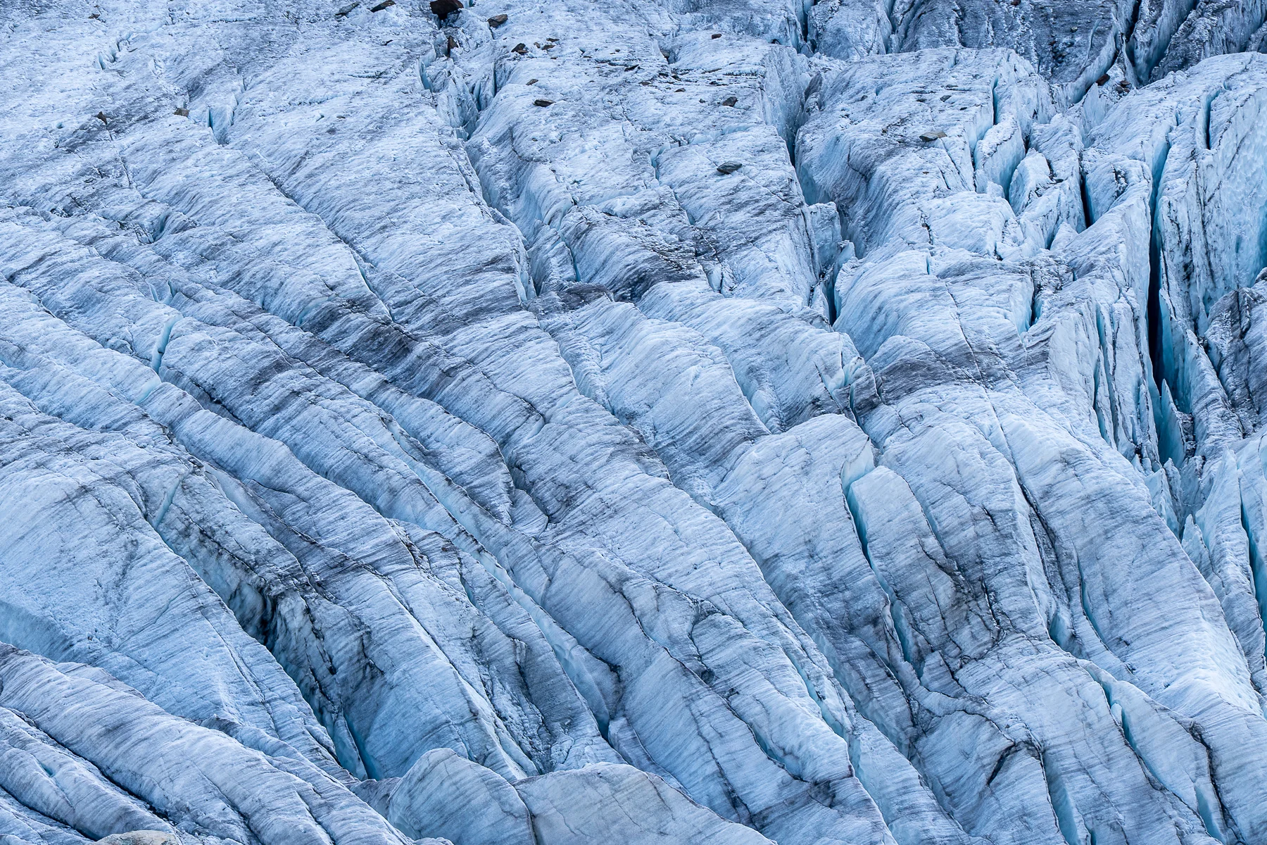 Nahaufnahme blauer Gletschereis-Formationen mit Spalten und Schichtlinien, Riedgletscher, Wallis, Schweiz