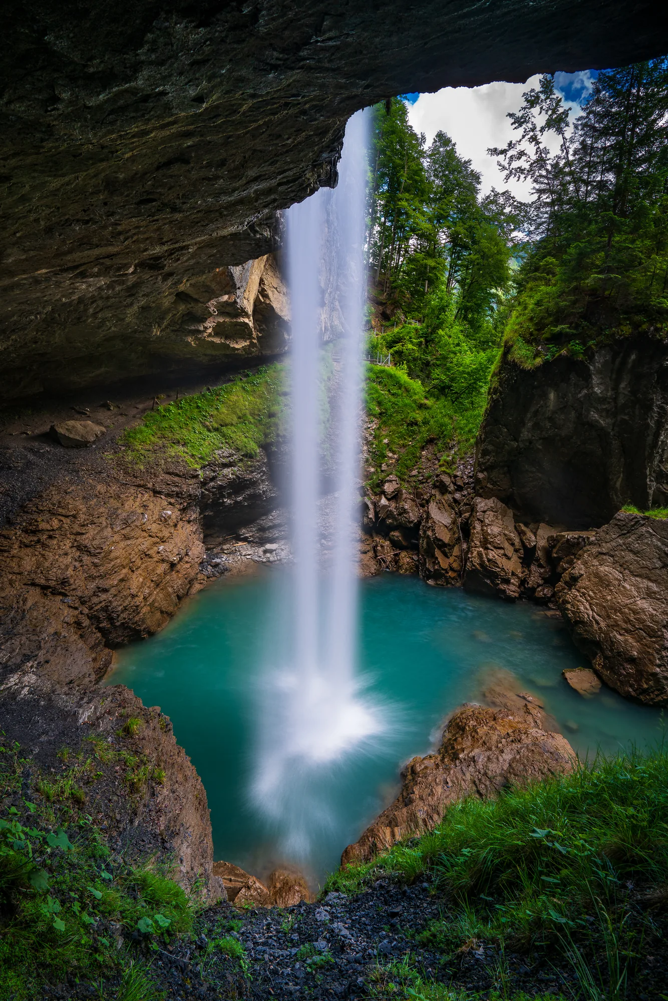 Mächtiger Wasserfall stürzt hinter Felsüberhang in türkises Becken, Blick aus der Höhle, Berglistüber, Glarus, Schweiz